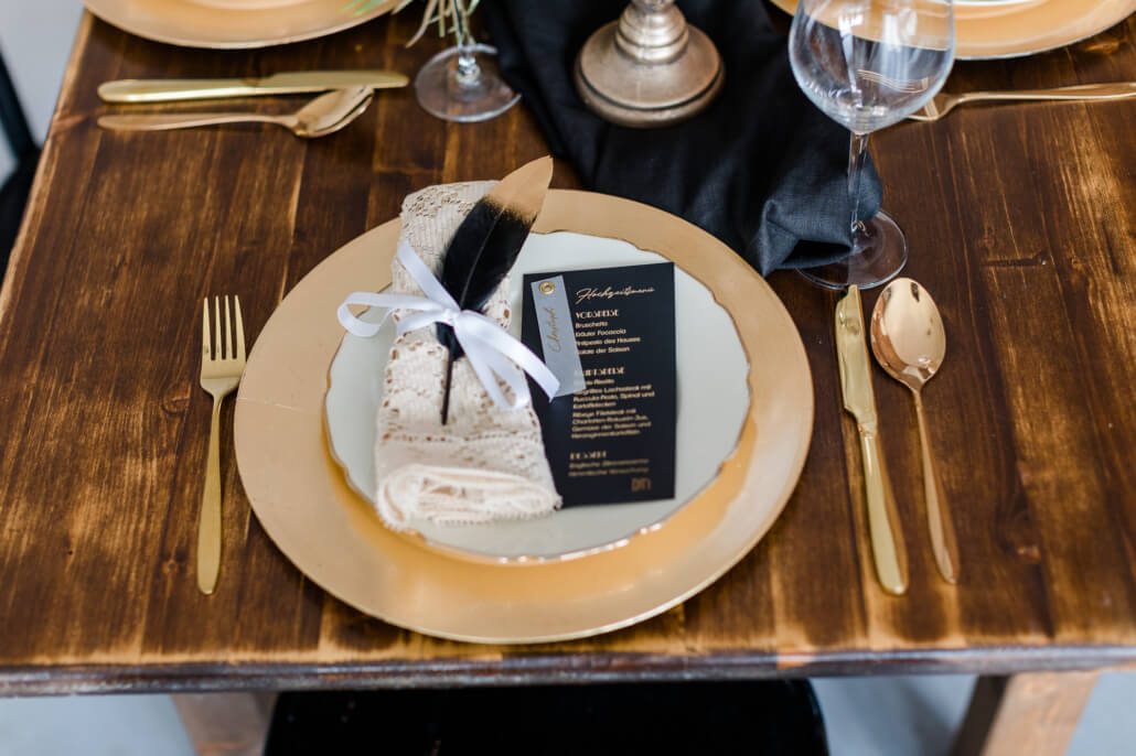Tischdeko mit Menükarte auf Teller in schwarz gold Great Gatsby Hochzeit